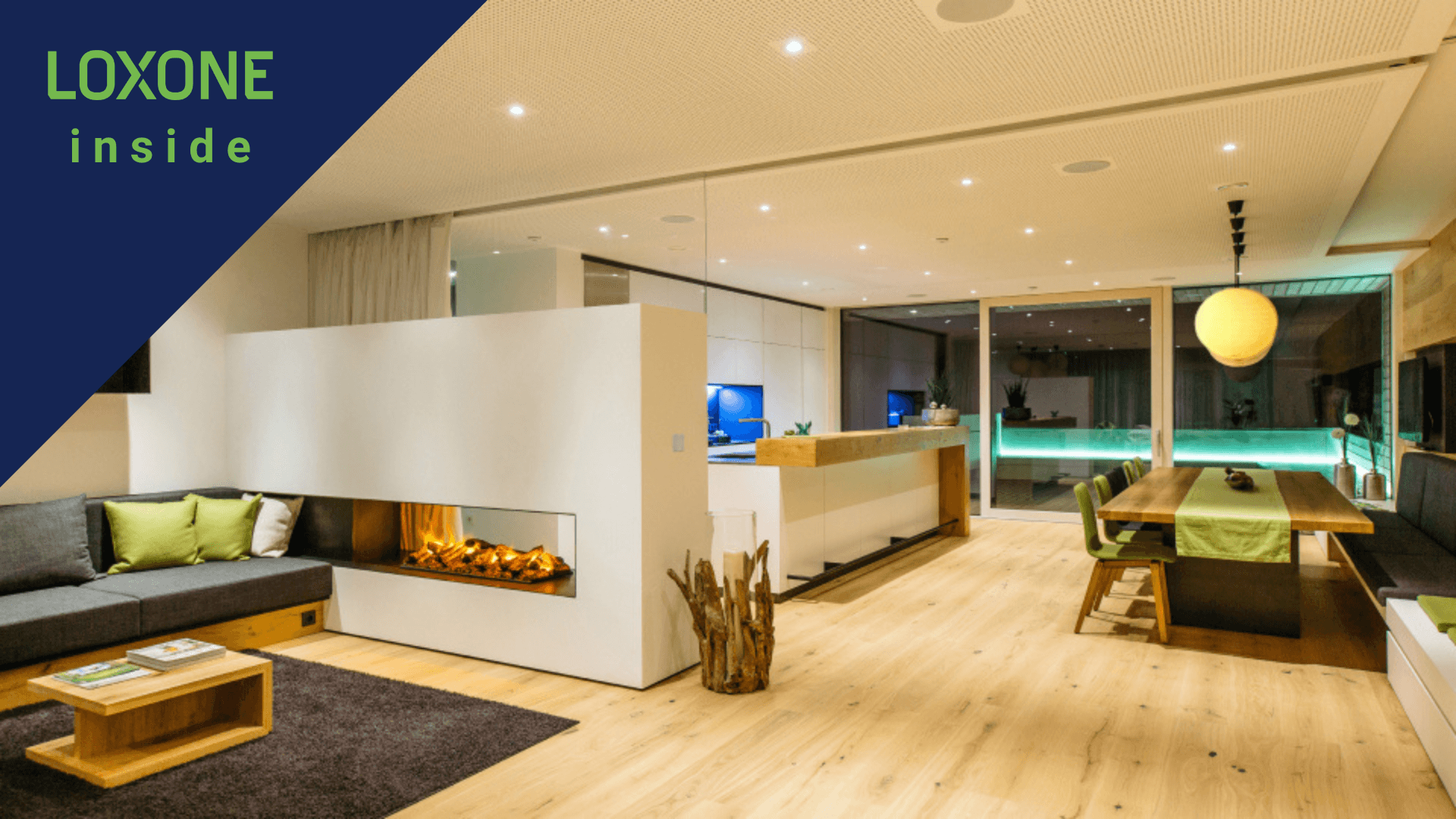 Modern gestalteter Wohnraum mit offener Küche, Kamin und indirekter Beleuchtung – Loxone inside
