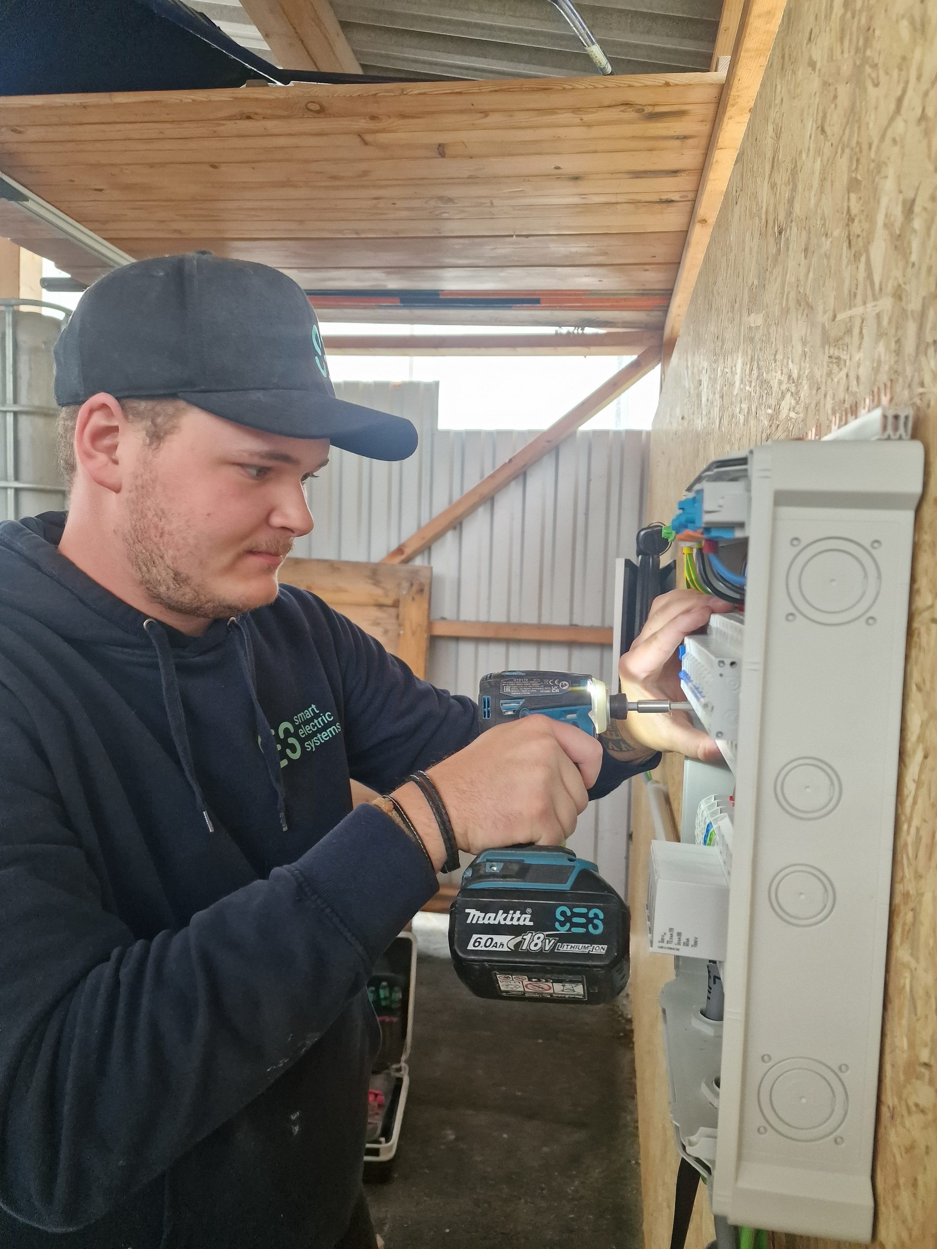 SES-Elektriker verdrahtet einen Sicherungsverteiler in einer Werkstatt mit dem Akkuschrauber.